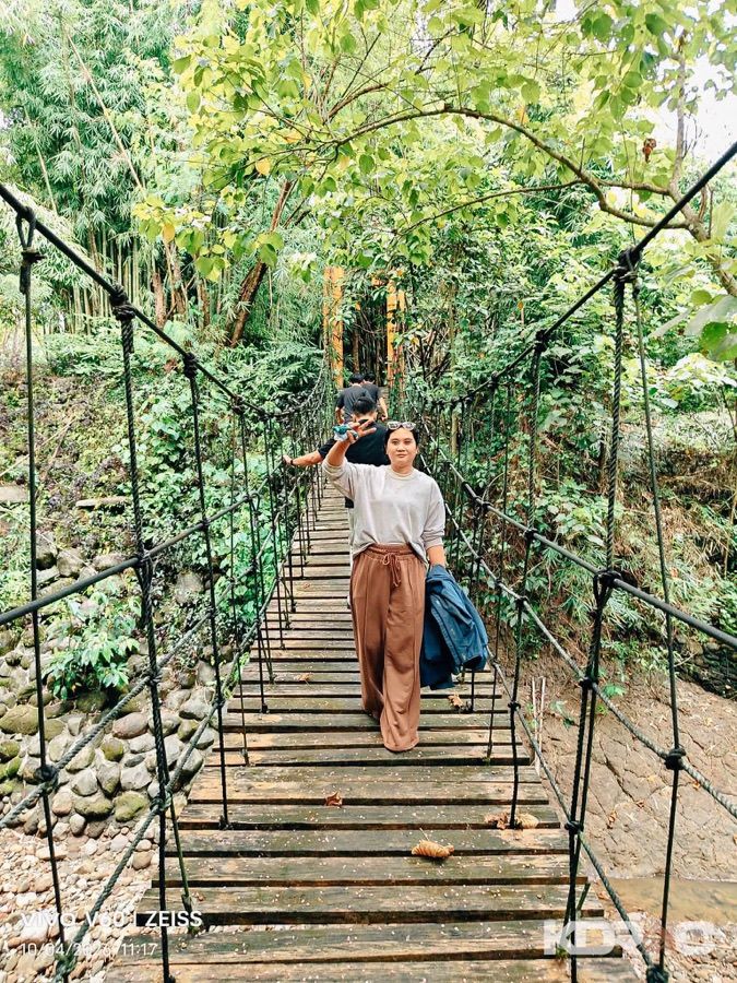 Visitor crossing the hanging bridge through the trees