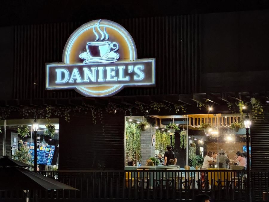 Daniel’s Coffee storefront at night with its lit sign
