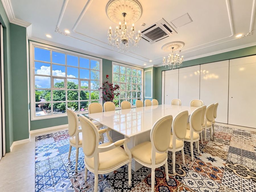 Green private dining room with a long white table and cream chairs