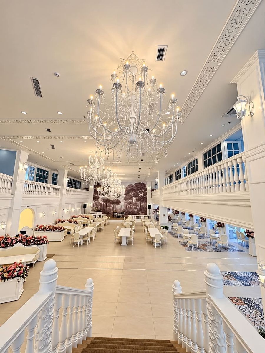 Dining hall seen from the stairs, with white railings and chandeliers