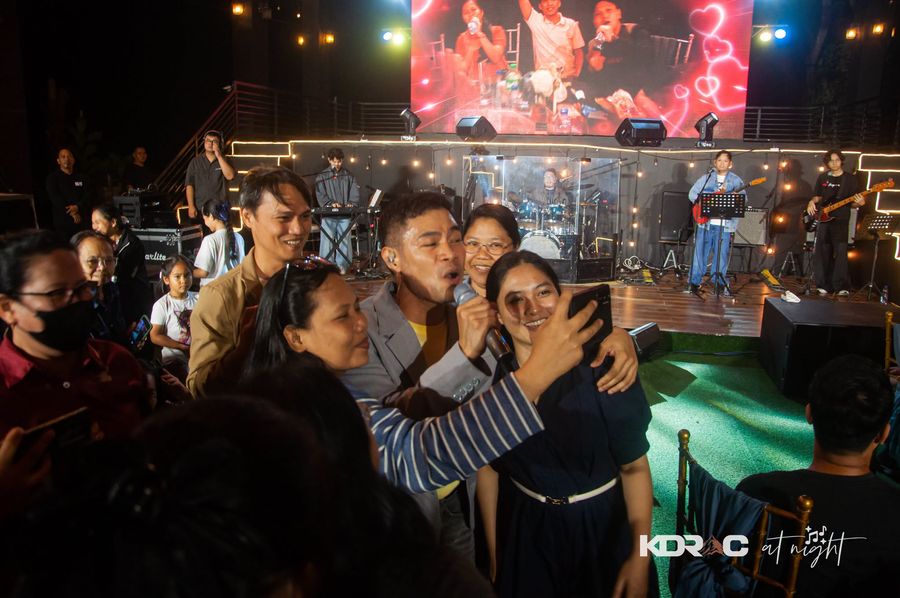 Guests taking selfies with the singer in front of the stage screen