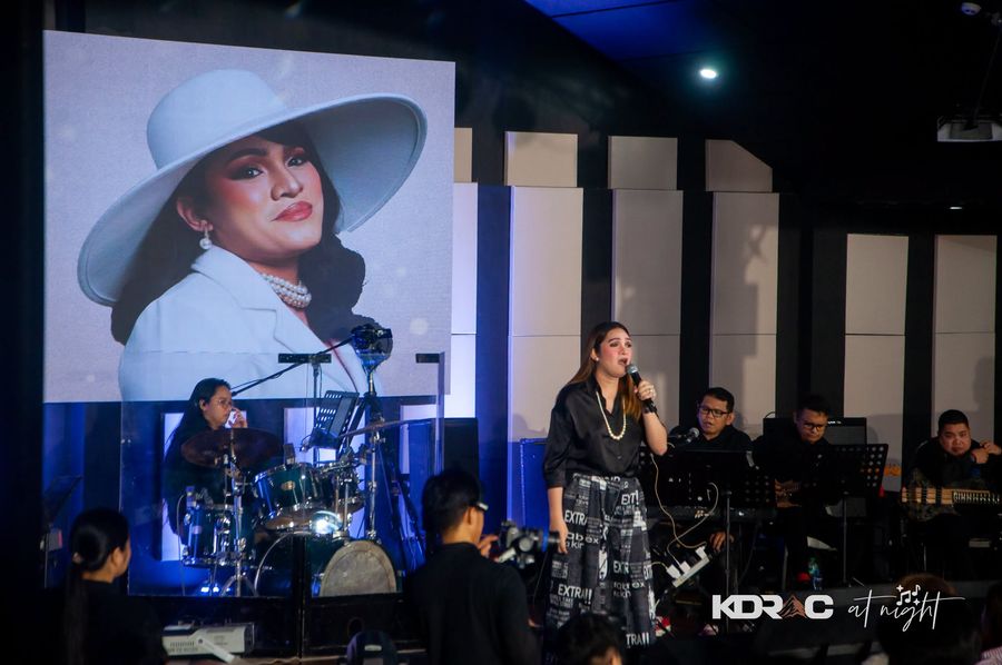 Singer in front of the big screen with her band on the stage