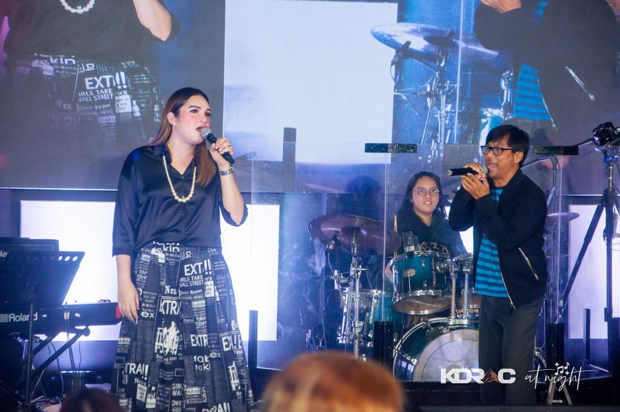Two singers sharing the stage in front of the drums